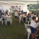 Bambini che giocano a scacchi su vari tavoli all'aperto