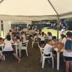 Bambini che giocano a scacchi su vari tavoli all'aperto