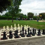 Scacchiera con pezzi in posizione iniziale su un tavolo con il parco come sfondo
