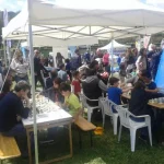 Partecipanti all'evento giocano a scacchi presso lo stand riservato alla FSI